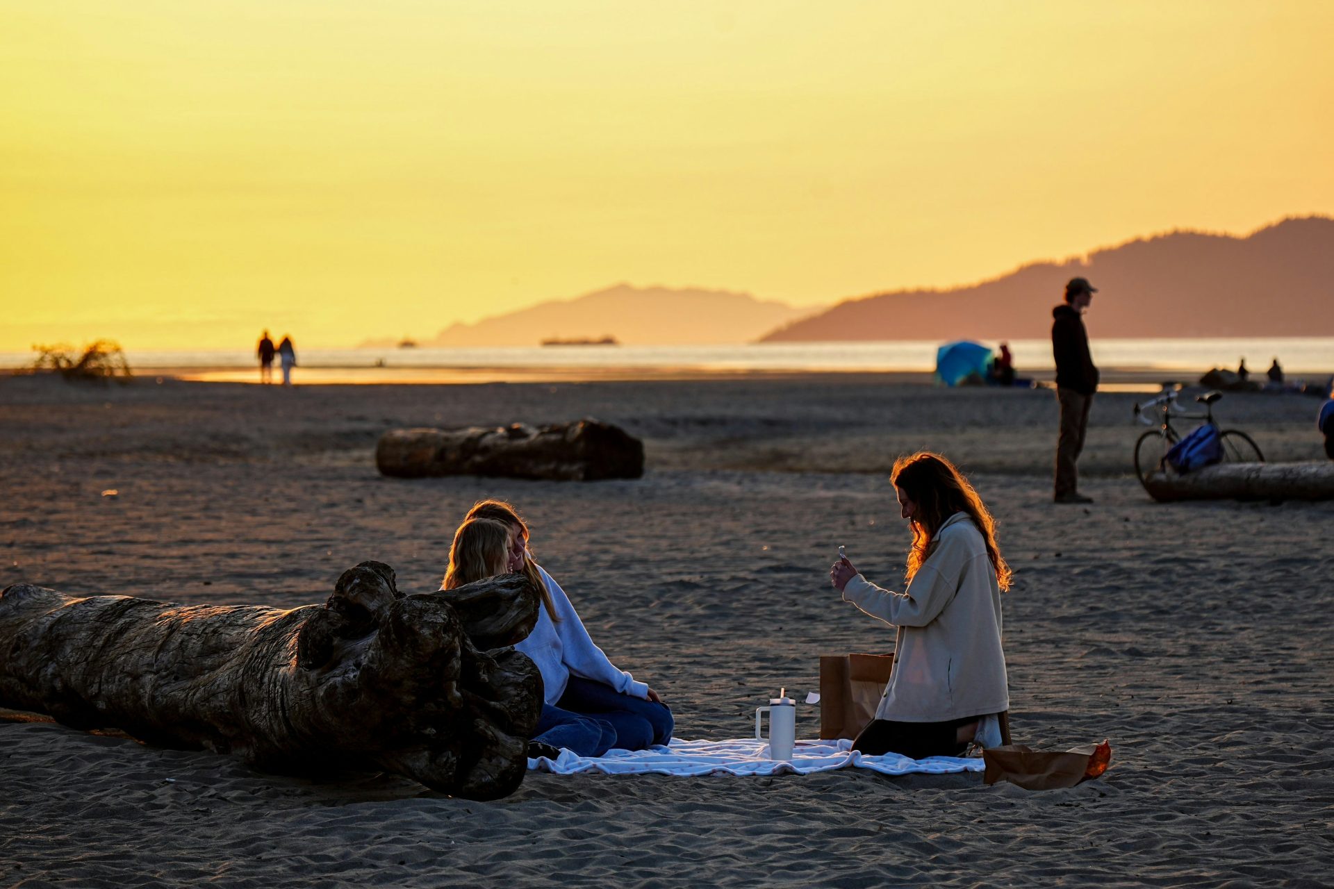 Two women having a picnic on a beach at sunset.